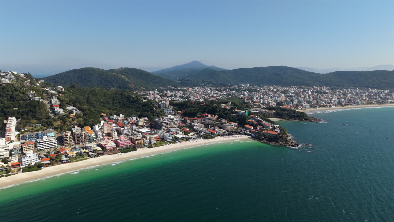 Aerial view of the Bombinhas coastal settlement with houses along both Praia de Bombinhas and Praia de Bombas sandy beaches, Bombinhas, Santa Catarina, Brazil