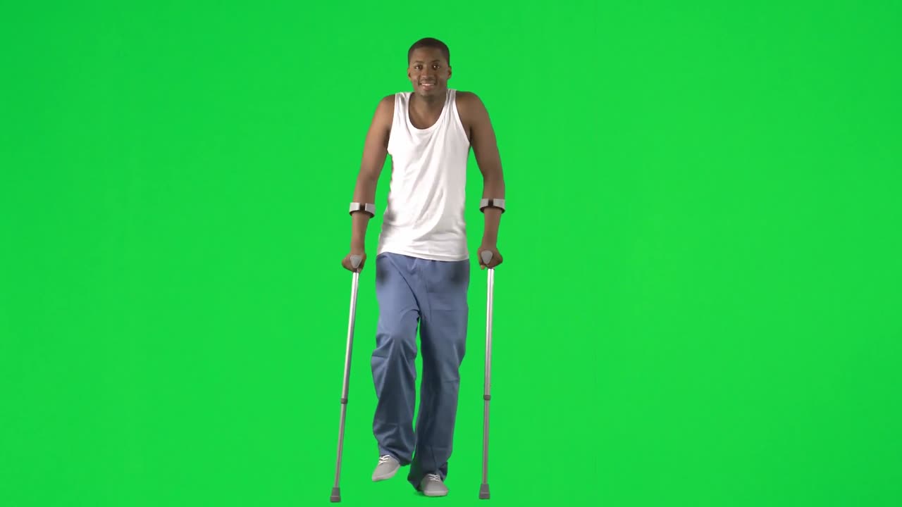 Ethnic young man walking with crutches footage