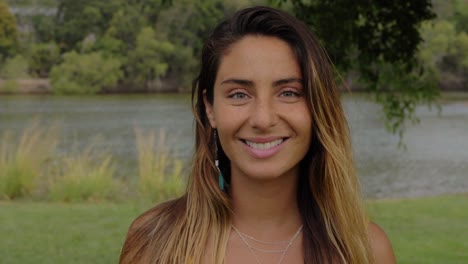 Hermosa-Mujer-Bronceada-Sonriendo-Mientras-Mira-La-Cámara-Junto-Al-Lago---Gold-Coast,-Queensland,-Australia