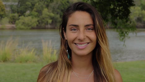 hermosa mujer bronceada sonriendo mientras mira la cámara junto al lago - gold coast, queensland, australia