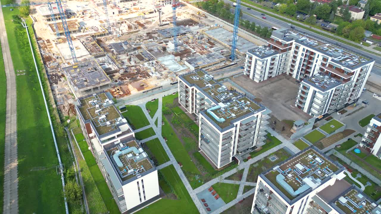 vista aérea de pájaro de un sitio de construcción construyendo grúas mirando hacia abajo área de maquinaria industrial alrededor de apartamentos urbanos residenciales