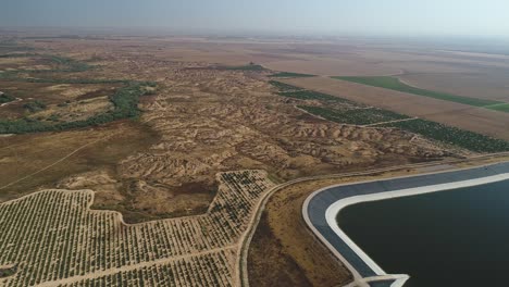 aerial footage of agricultural water reservoir in a large area of fields
