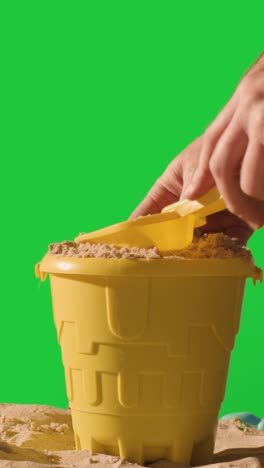 Vertical-Video-Summer-Holiday-Concept-Making-Sandcastle-On-Sandy-Beach-Against-Green-Screen