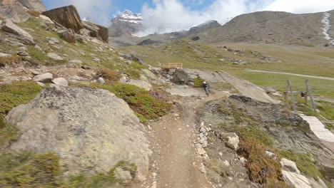 fpv drone follows two mountain bikers descending steep, exposed alpine trails above saas-grund and saas-fee on a clear bluebird summer day, showcasing epic terrain and speed
