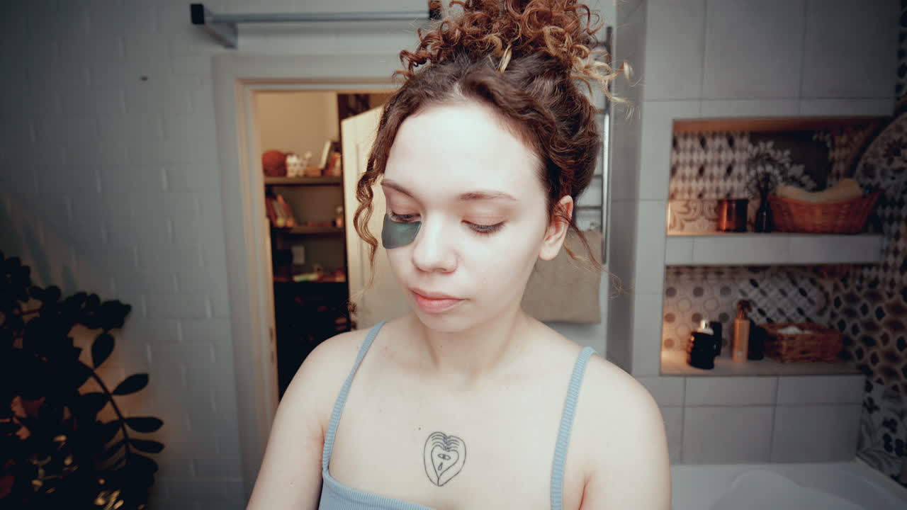 Beautiful Girl Applying Under-Eye Patches during Skincare Routine in Bathroom