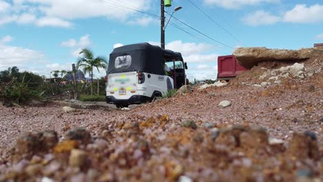 truck and tuk tuk driving on a dirt road