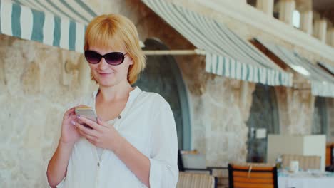 Attractive-Woman-Writing-Sms-On-A-Background-Of-A-Typical-Italian-Restaurant