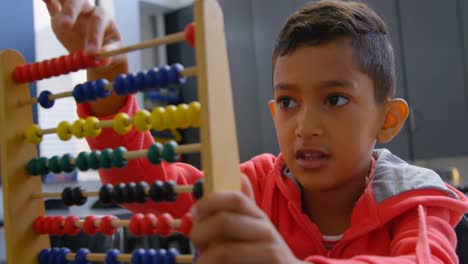 front view of asian schoolboy solving math problem with abacus at desk in a classroom at school 4k