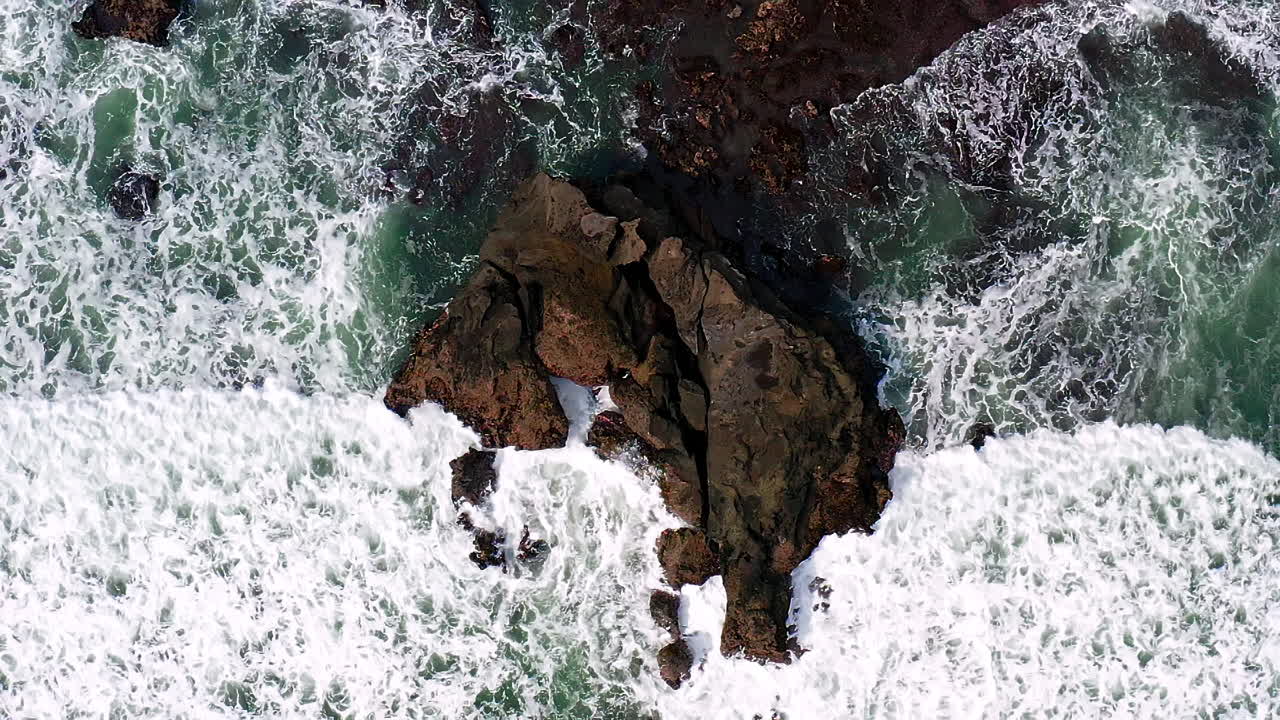 Roccia frastagliata e appuntita su costa rocciosa bagnata da grande onda marina spumeggiante