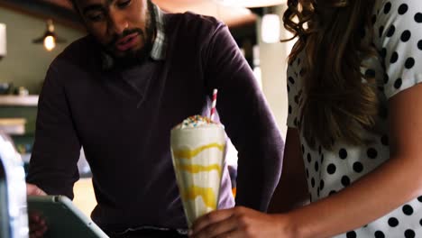 Couple-using-digital-tablet-while-having-smoothie-in-pub