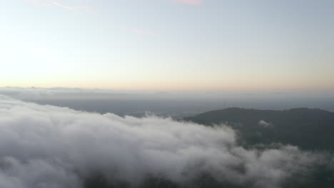 Drone-ascent-and-looking-left-over-low-cloud-and-tv-communication-towers-during-dusk