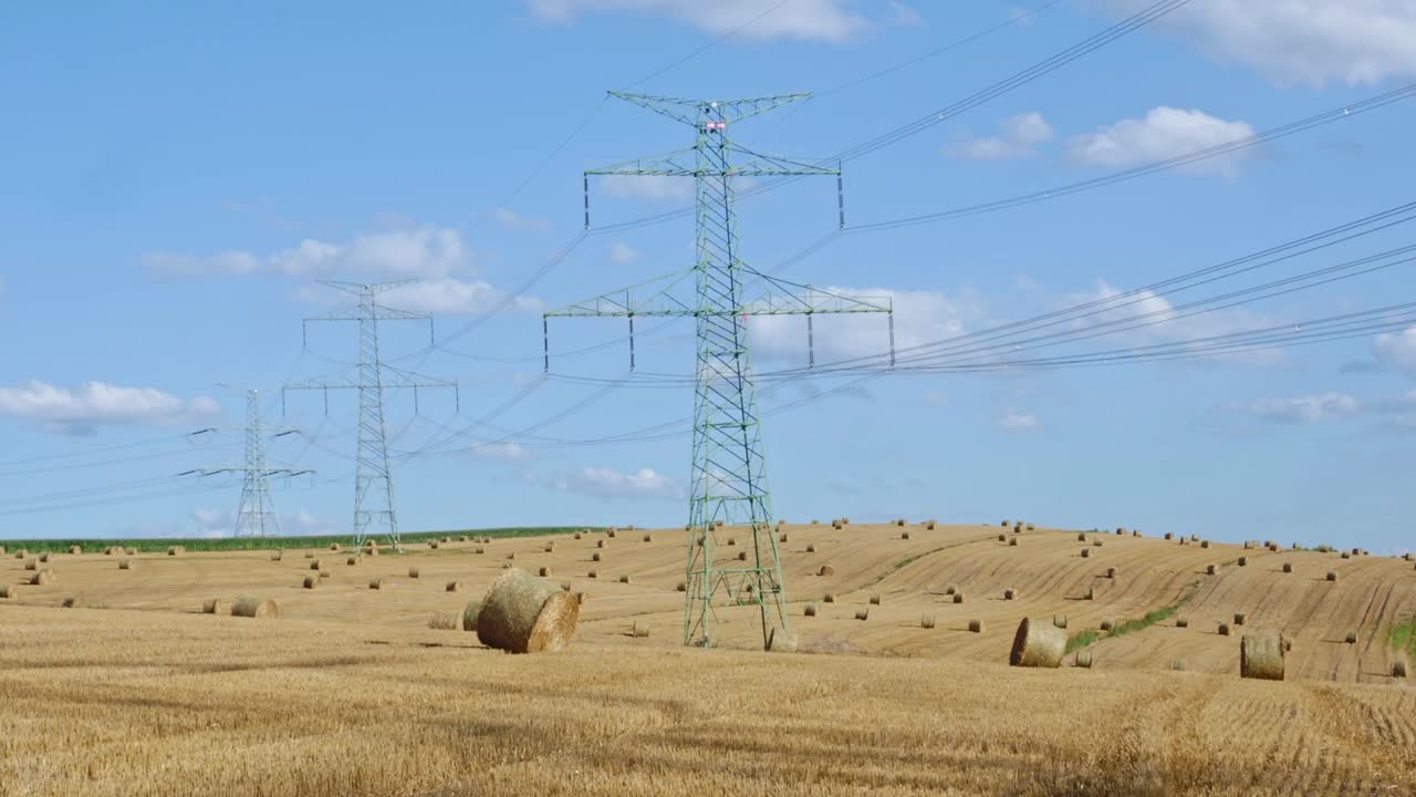 Fardos de palha no campo perto de postes de alta eletricidade