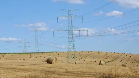 balas de paja en el campo cerca de altos pilares de electricidad