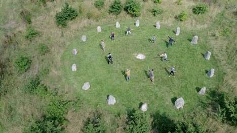 un grupo de personas practican artes marciales zen como palo en un antiguo círculo de piedra