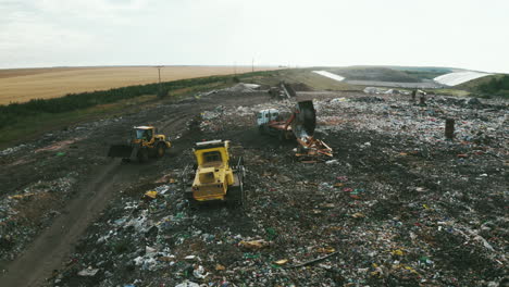 high-quality footage of landfill with geomembrane, garbage trucks and tractors processing and shredding waste, drone shots, nature surrounding energy plant chimneys, showcasing environmental themes