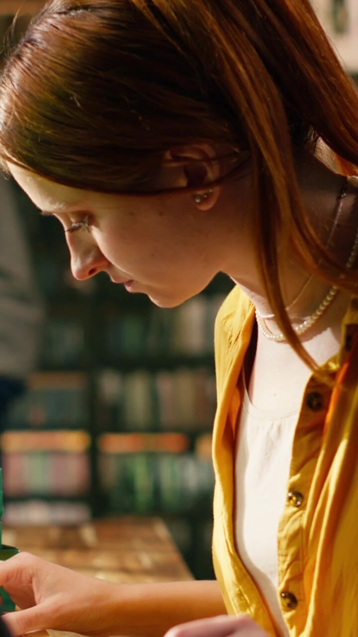 Video verticale: Giovane studente legge un libro aperto e digita sul laptop.