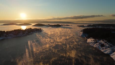 Puesta-De-Sol-De-Hora-Dorada-En-El-Horizonte-Cerca-De-Bjorvika,-Oslo-Con-Niebla-Flotando-Sobre-El-Agua