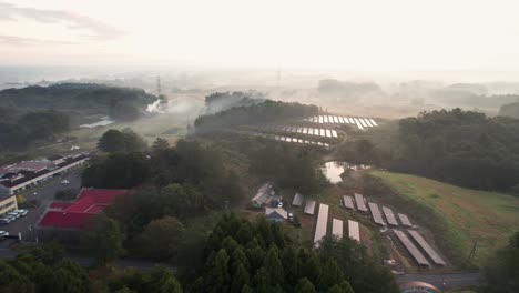 Luftdrohne-Fliegt-über-Asiatische-Häuser-Mit-Sonnenkollektoren-Auf-Landwirtschaftlichen-Feldern,-Sonnenuntergangs-Skyline-Am-Stadtrand-Von-Japan