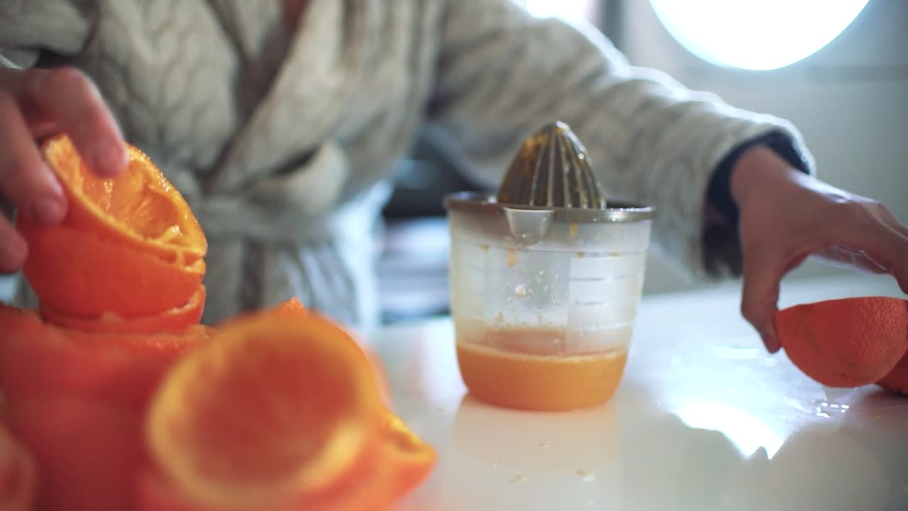 Mujer usando un exprimidor de naranjas, preparando un zumo de naranja en casa.