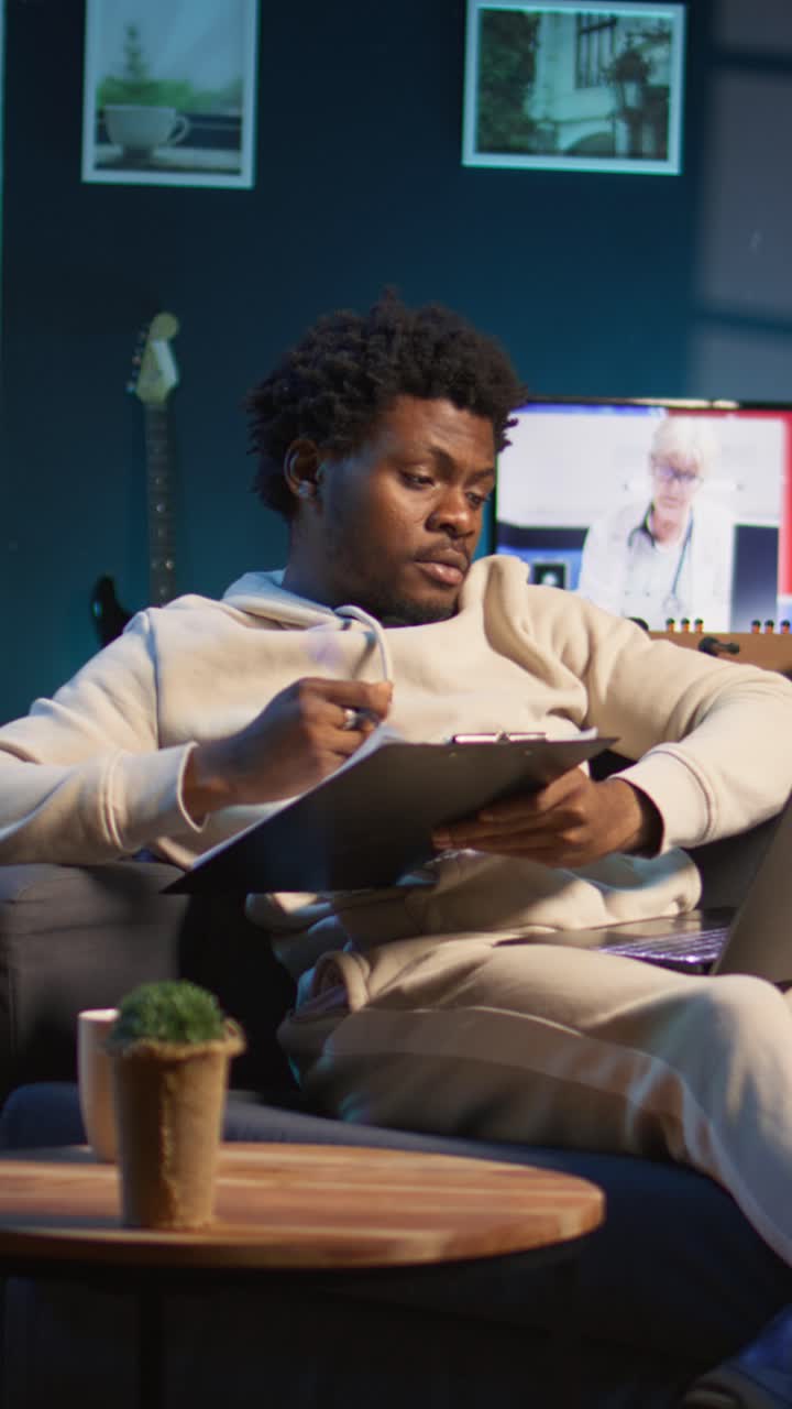 African American Man Working on Laptop and Writing at Home