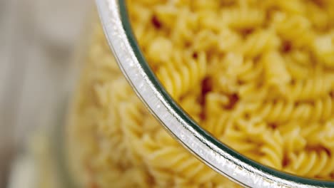 close-up of colored and original fusilli pasta in transparent jar glass