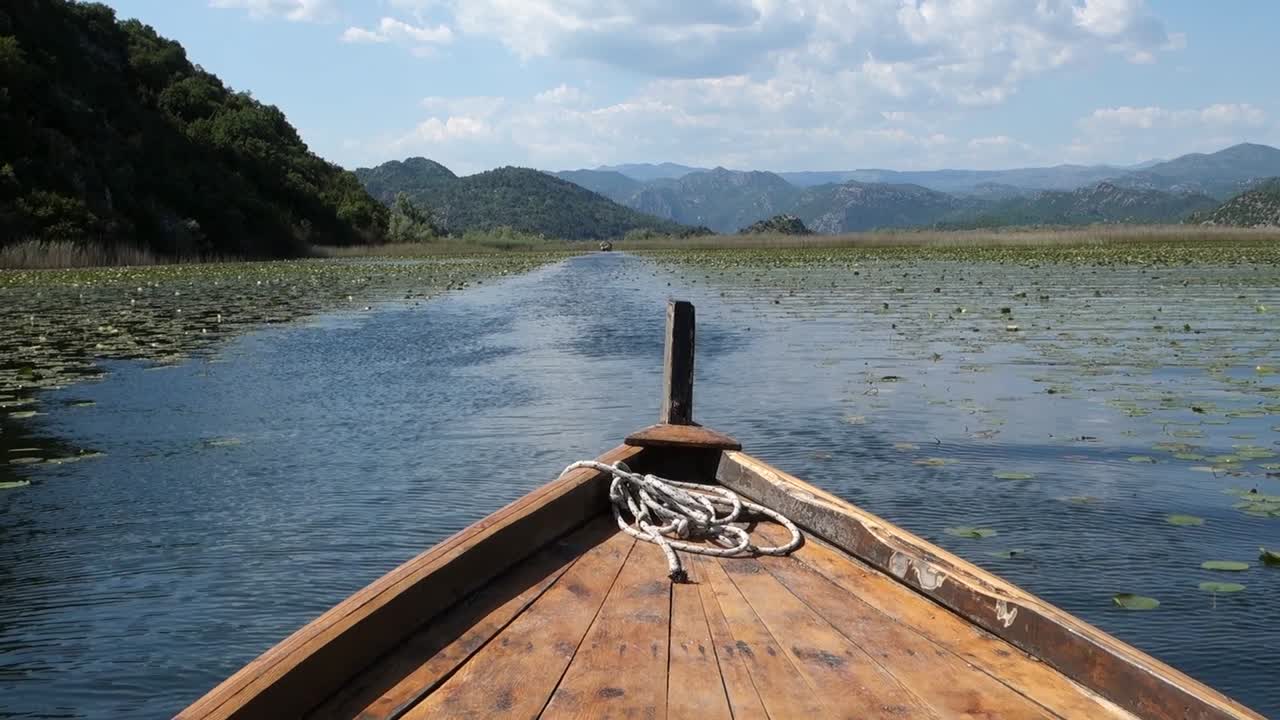 wooden raft sails on calm waters of Lake Skadar, on the border of Albania and Montenegro. Largest lake in Southern Europe