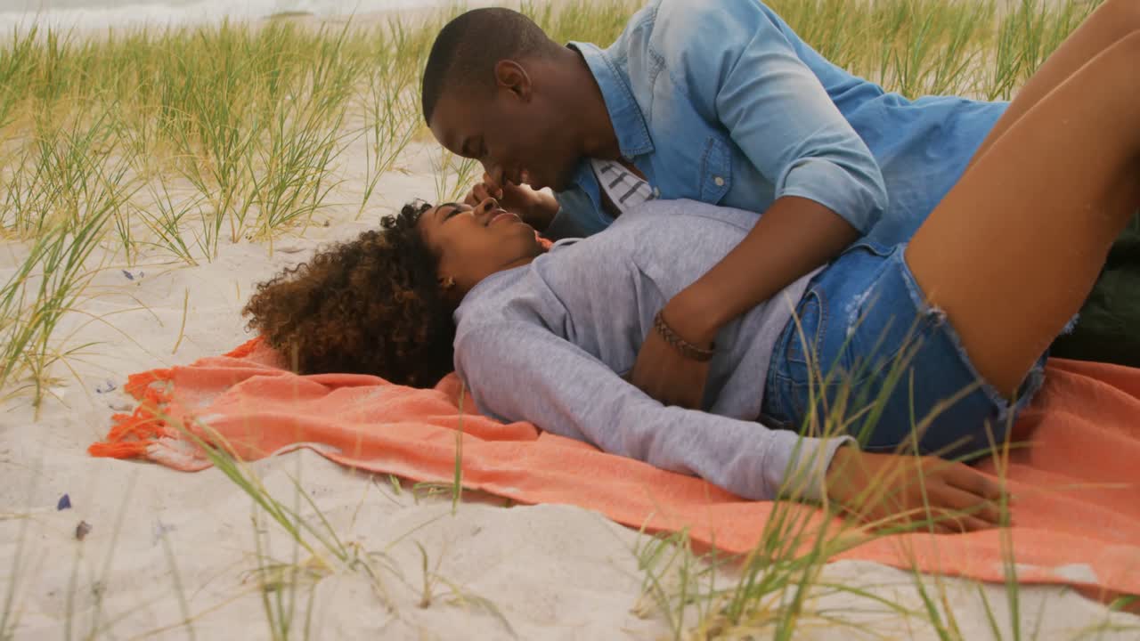 vista lateral de una pareja afroamericana divirtiéndose en la playa 4k