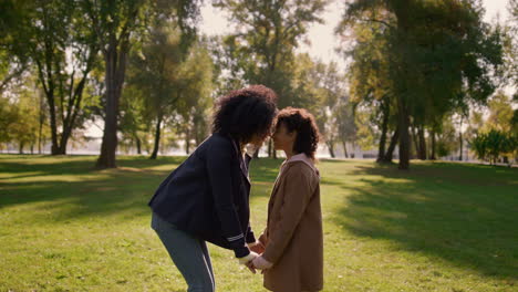 Cute-daughter-touching-noses-with-lovely-mother-standing-on-field-park-closeup