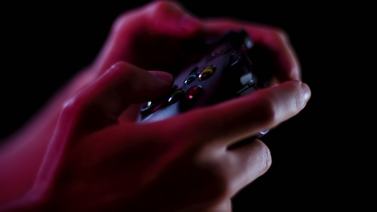 Playing video games in a darkened room with a black background close up on a controller buttons playing quickly