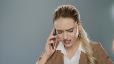 annoyed business woman calling mobile phone on gray background