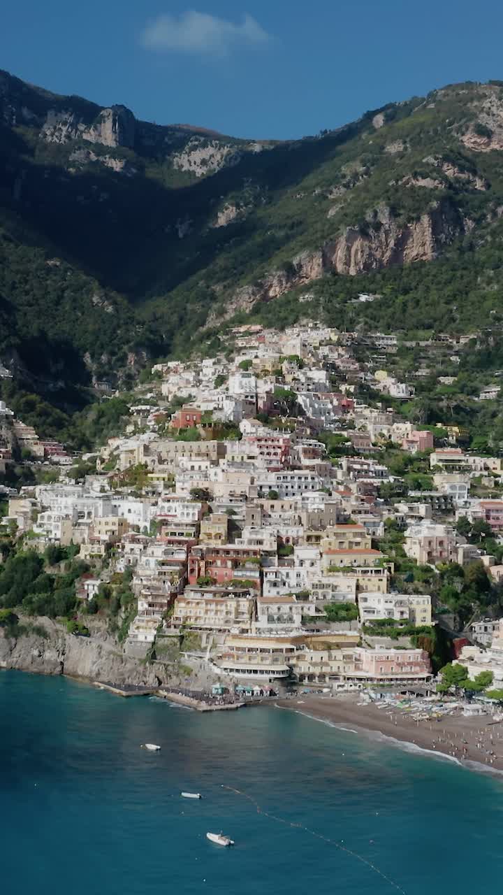 Vista aerea verticale di Positano sulla Costiera Amalfitana in Italia. Colorato villaggio sulla scogliera sopra il Mar Mediterraneo turchese. Vacanze sulla costa italiana in una giornata estiva soleggiata con cielo azzurro limpido