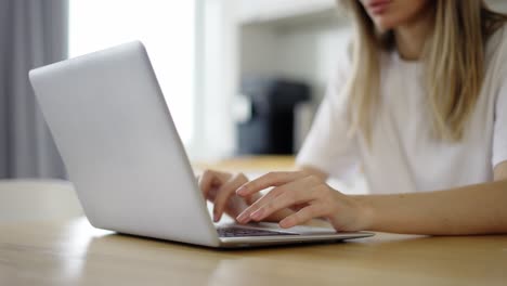 mujer concentrada escribiendo en una computadora portátil en casa