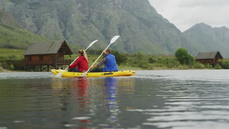 caucasian couple having a good time on a trip to the mountains, kayaking together on a lake