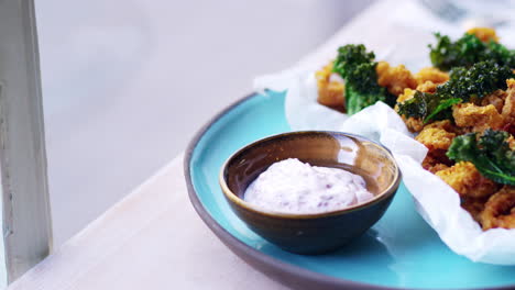 fried squid, kale and sumac mayo by a window, close up pan