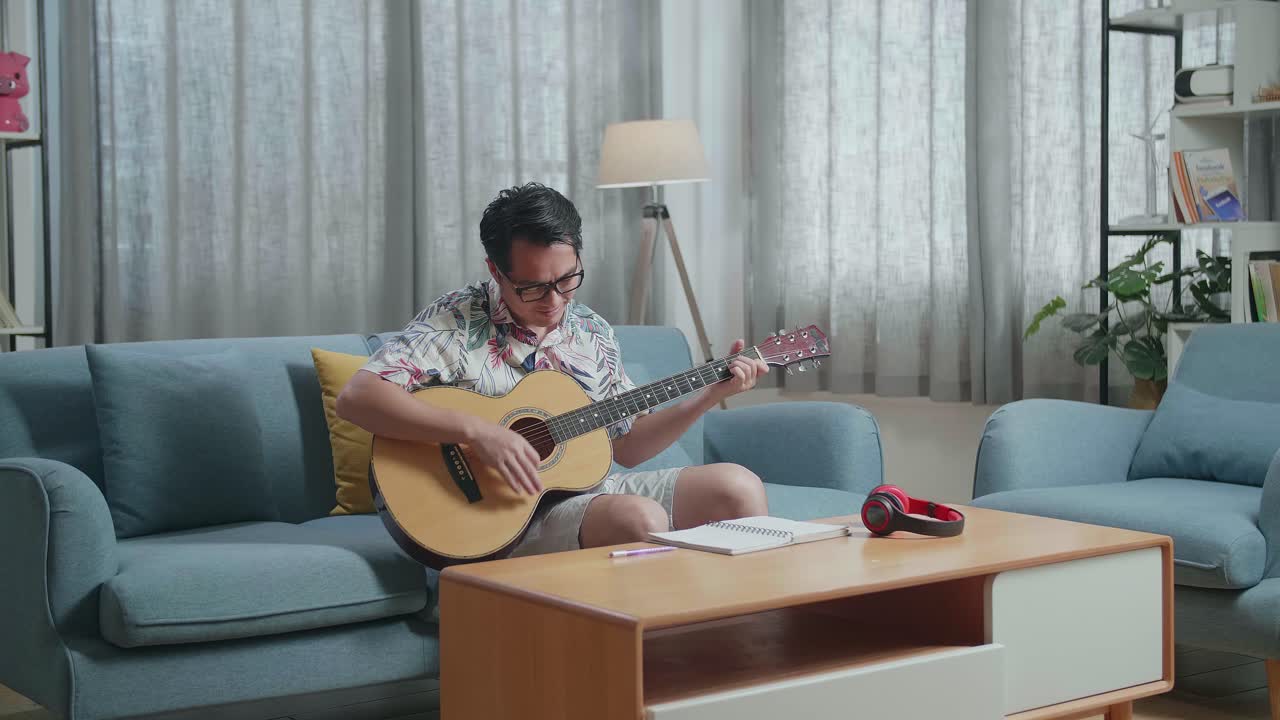집에서 기타를 연주하는 테이블 위에 노트북을 가진 아시아인 작곡가