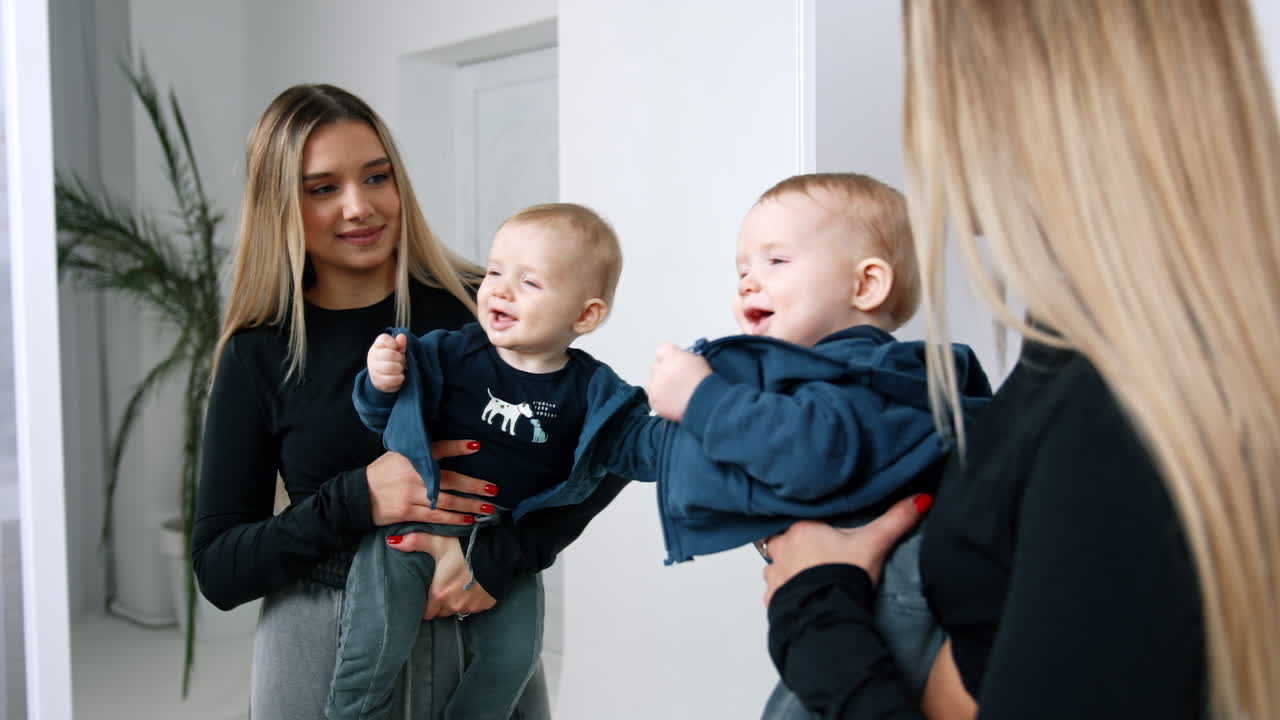 Blond Caucasian long-haired woman standing holding a little cute baby. Mother and son standing near the mirror.