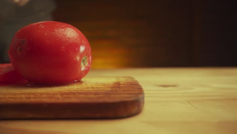 hands-in-white-gloves-slicing-a-tomatoe-with-a-knife-over-a-wooden-table