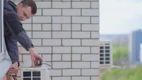 el asistente comprueba la instalación correcta de la unidad de aire acondicionado. fijación e instalación de una unidad de aire acondicionado externa en un piso alto. instalación peligrosa de sistemas de refrigeración de aire.