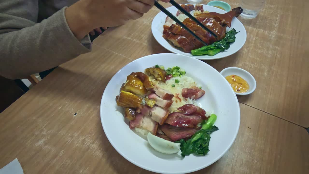 香港の地元レストランで、本格的な人気の広東料理「燒味（シウメイ）」、またはローストミートを囲んで食事を楽しむ2人のハイパーラプス。