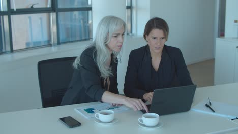 colegas de oficina enfocados usando portátiles juntos,