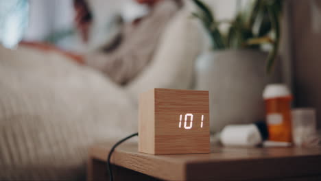mujer en la cama con un despertador digital en la mesa de noche