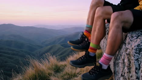 hikers with colorful socks enjoying a panoramic mountain view at sunset