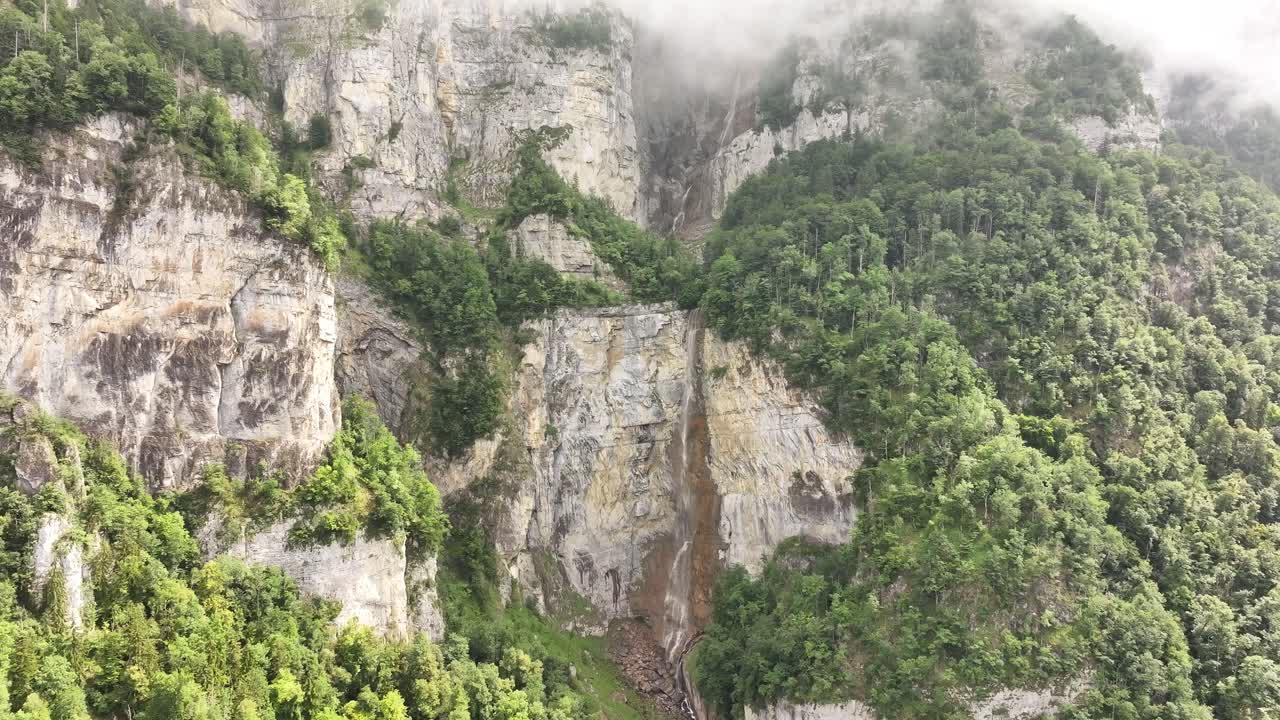 Seerenbach waterfall in Switzerland aerial view, flowing down rocky cliffs with lush green forest