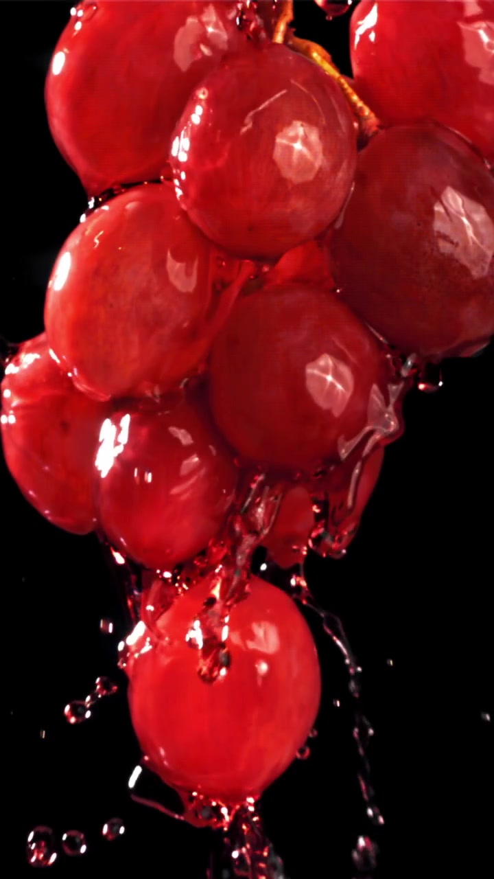 Liquido rosso che si versa al rallentatore su uva rossa fresca