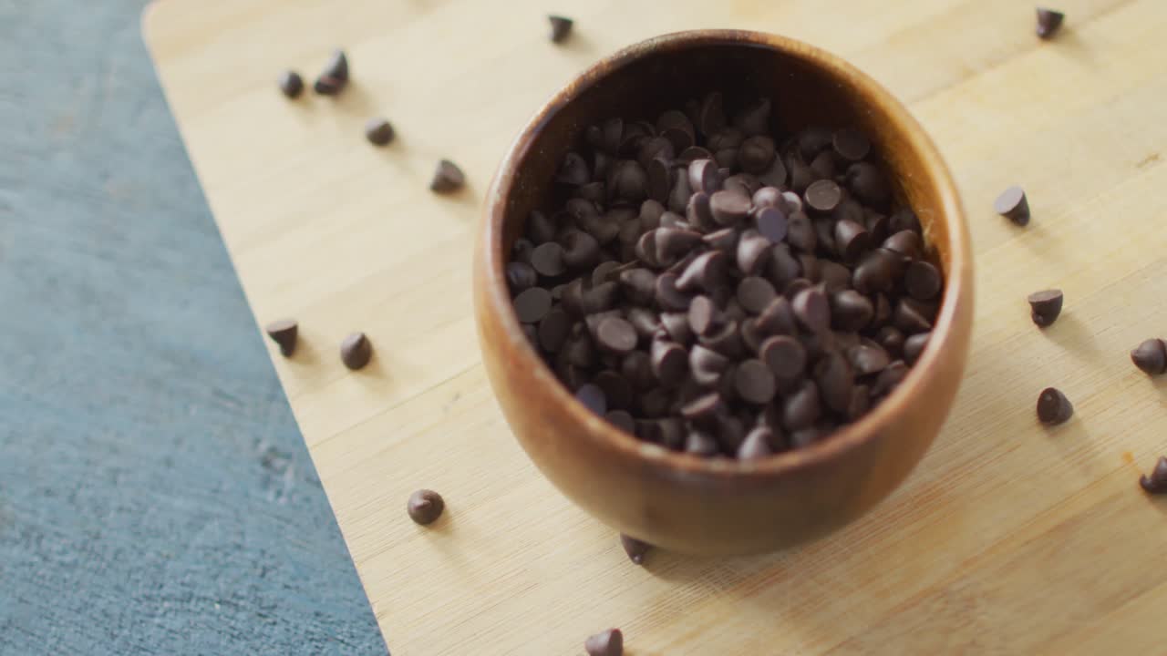 Video di primo piano di ciotola con gocce di cioccolato biologiche su sfondo di legno