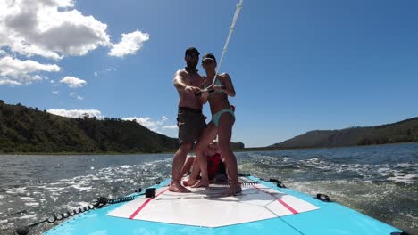 speedboat towing a family on their paddle board. point of view from the deck