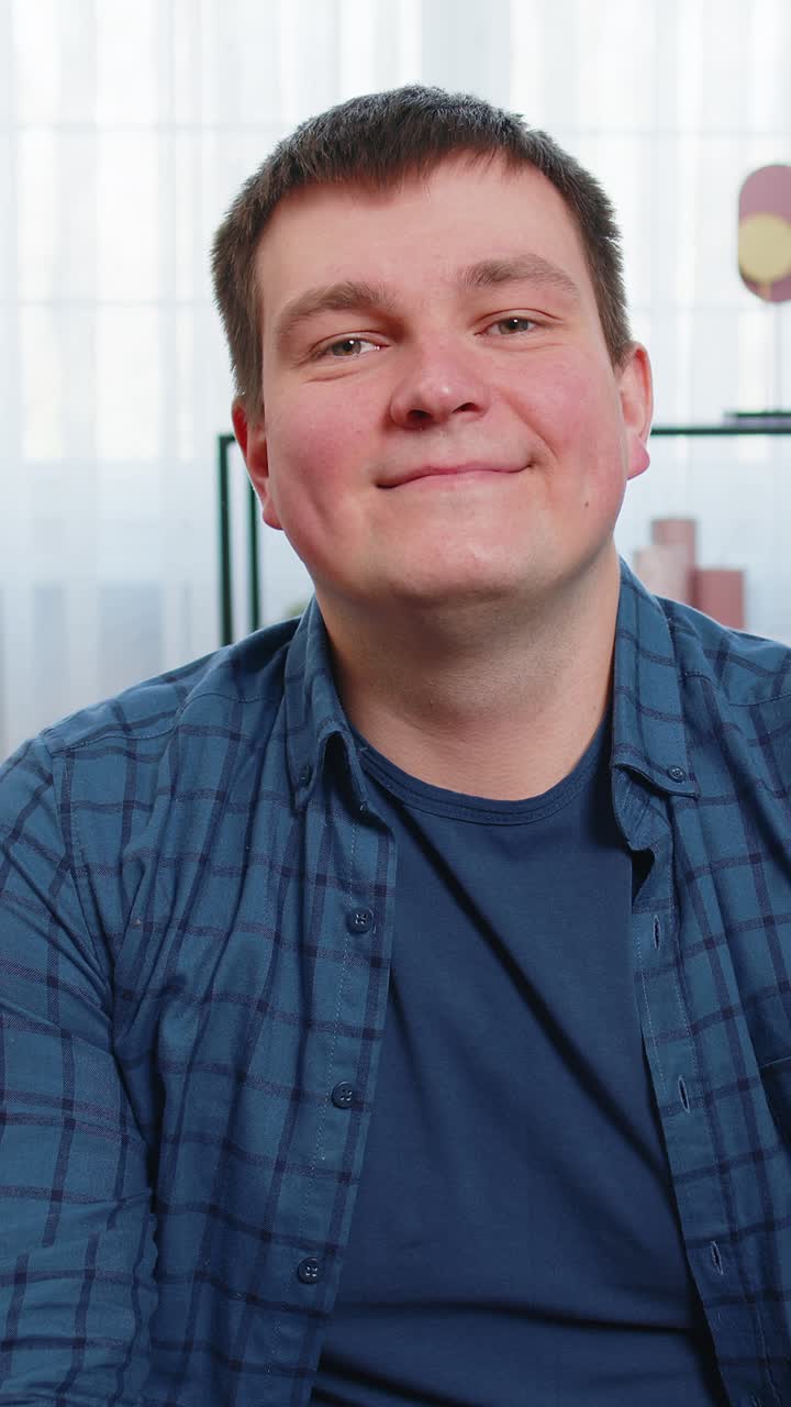 Portrait of happy caucasian man sitting on couch looking at camera and smiling relaxing at home