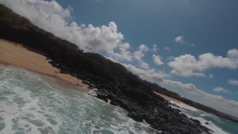 slow motion of some unrecognised tourists bathing with waves crashing on paradise island next to tourists in hawaii from fpv race drone