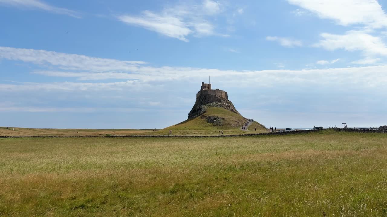 Lindisfarne Castle on hill surrounded by green fields and blue sky. Holy Island, Northumberland - UK
