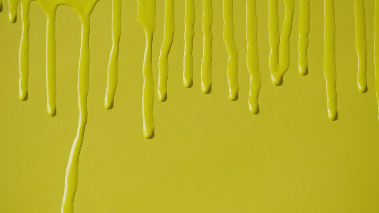 Bright Yellow Paint Dripping Down a Smooth Surface